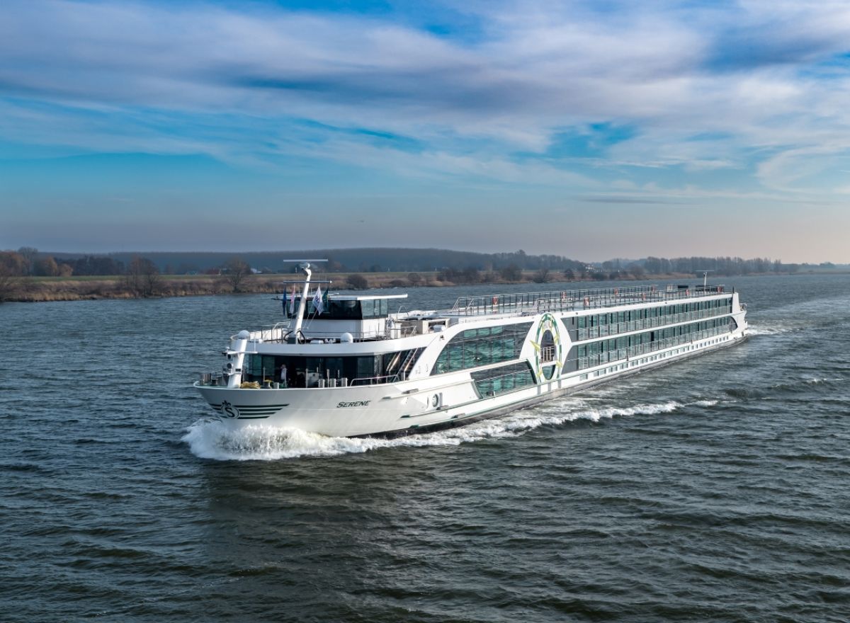 Close-up view of the Lumière river cruise ship underway, featuring its contemporary white exterior, large glass façades, and Dutch flag.